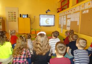 Dzieci oglądają prezentację multimedialną o Unii Europejskiej.